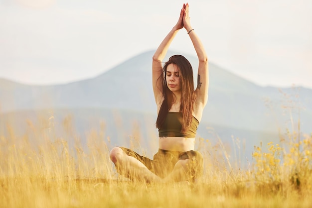 Beautiful young woman doing yoga exercises Majestic Carpathian Mountains Beautiful landscape of untouched nature