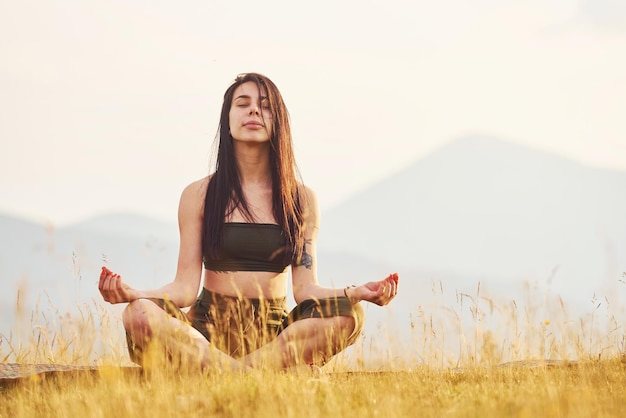 Beautiful young woman doing yoga exercises Majestic Carpathian Mountains Beautiful landscape of untouched nature