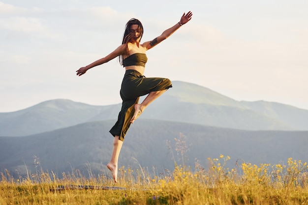 Beautiful young woman doing yoga exercises Majestic Carpathian Mountains Beautiful landscape of untouched nature