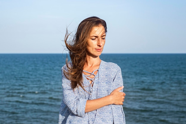 Beautiful young woman in dress on the cliff against the background of the sea.