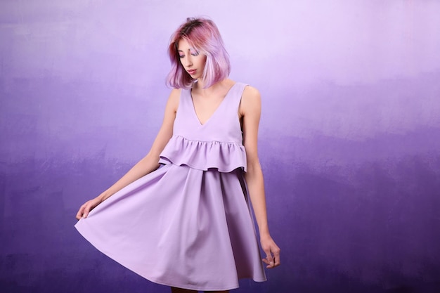 Beautiful young woman in dress on lilac background