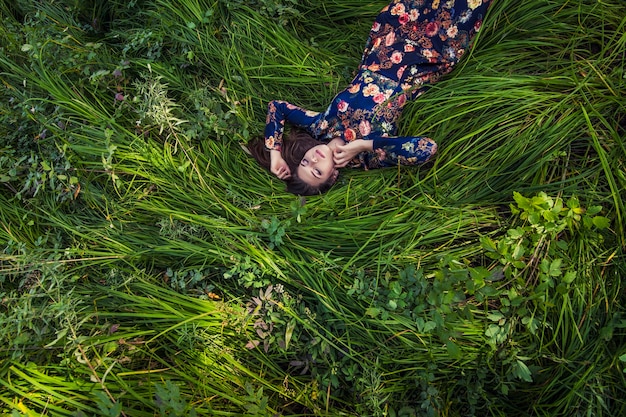 Beautiful young woman in dress lying in the grass in nature