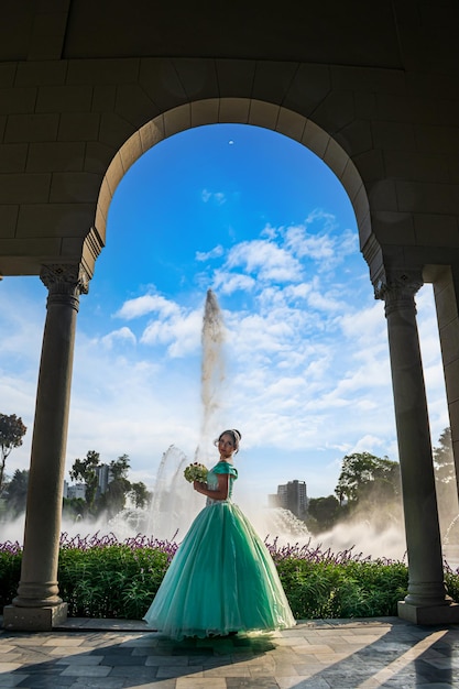 Beautiful young woman dressed in princess costume in the arch of a palace