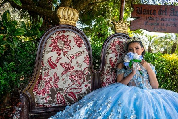 Beautiful young woman dressed in a princess costume sitting on an armchair in a park.