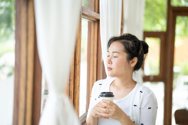 窓際でコーヒーを飲む美しい若い女性