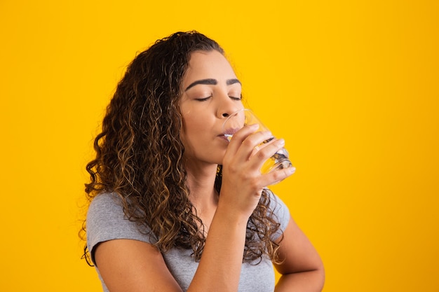 新鮮なコップ一杯の水を飲む美しい若い女性