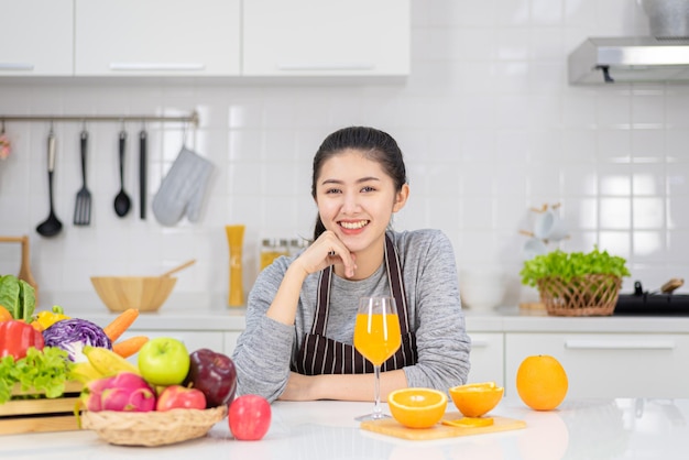 부엌에서 신선한 오렌지 주스를 마시는 아름 다운 젊은 여자. 건강한 식단