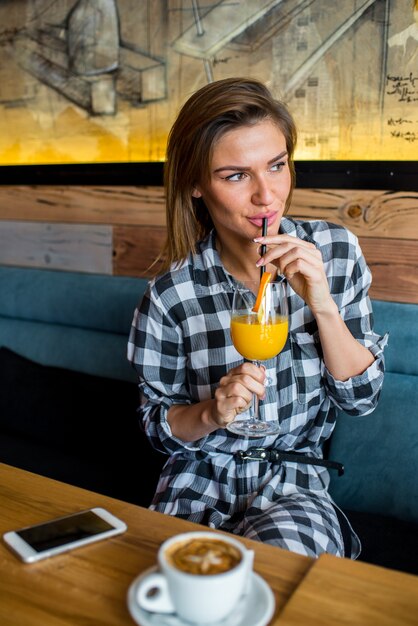 Foto bella giovane donna che beve il succo di arancia