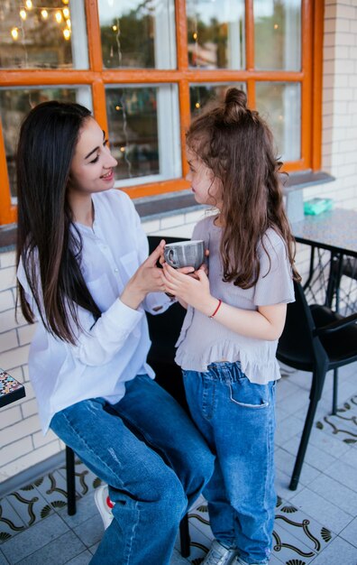 A beautiful young woman drinks tea with her little daughter Family leisure and recreation