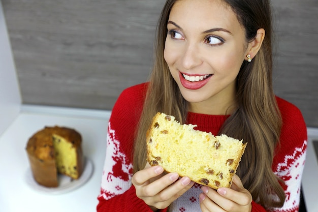 Beautiful young woman eating a slice of Panettone on Christmas holiday