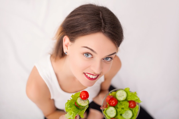 Bella giovane donna che mangia insalata di verdure