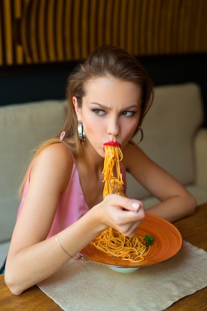 写真 美しい若い女性がレストランでスパゲッティを食べる