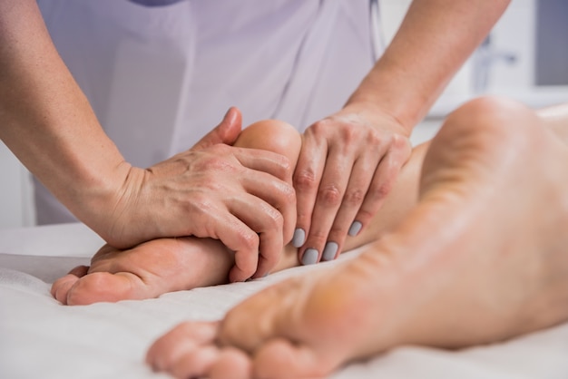 Beautiful young woman enjoying foot massage in spa salon.