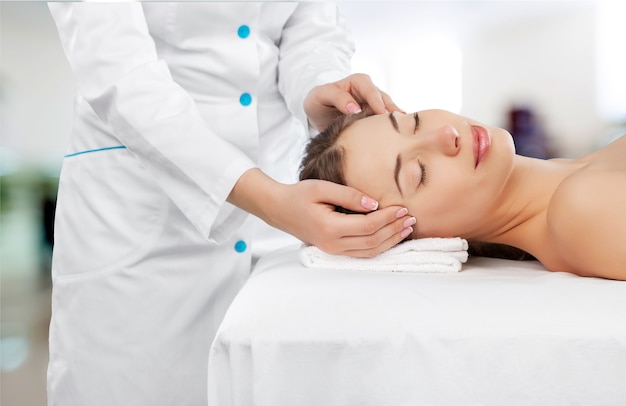 Beautiful young woman enjoying head massage in spa center