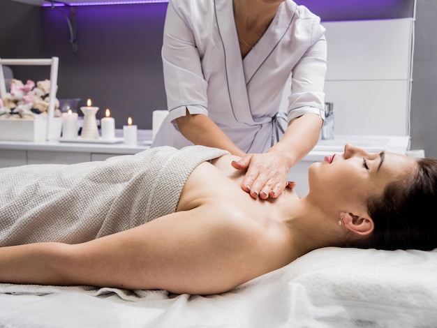 Beautiful young woman enjoying massage in spa salon. Cosmetology