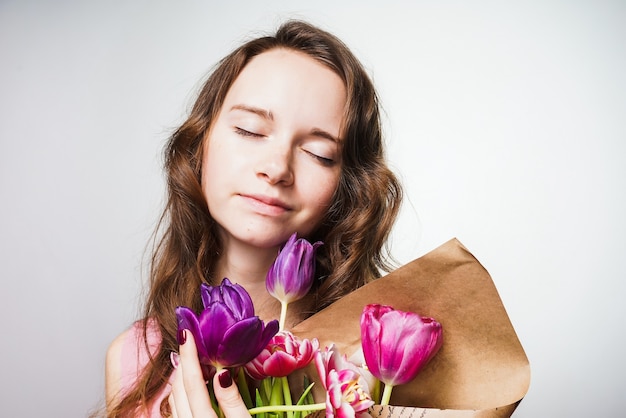 春を楽しんで、香りのよい花の花束を持って、世界女性の日を待っている美しい若い女性