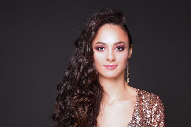 Beautiful young woman in evening dress on black background