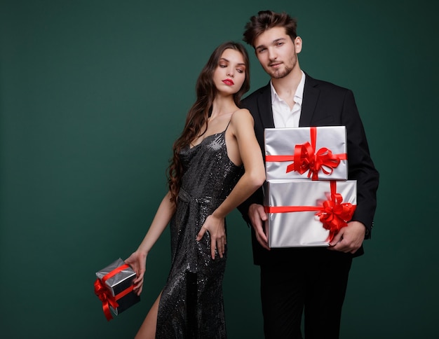 Beautiful young woman, evening makeup  stylish dress , brunette, and young man in suit, gifts boxes