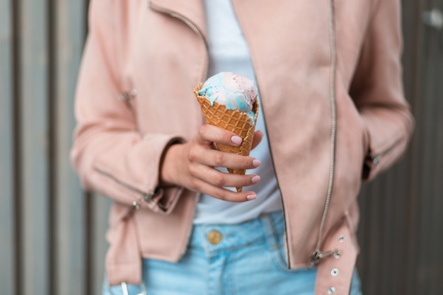 Photo beautiful young woman in a fashion pink jacket and shorts holding a tasty ice cream