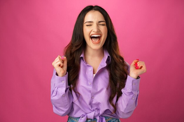 beautiful young woman feeling very excited and raising her arms celebrating success