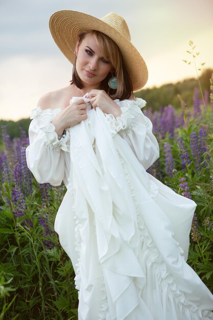 Beautiful young woman in a field of blooming lupines