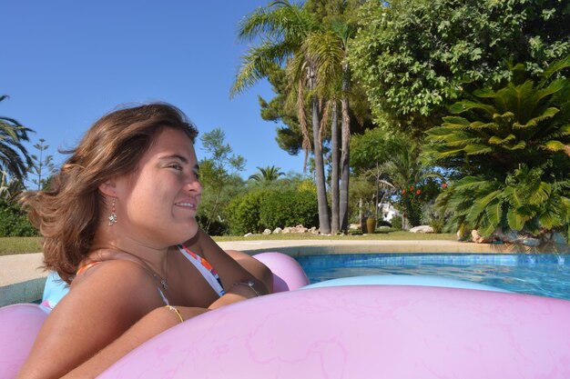Foto bella giovane donna che galleggia su una piscina in una giornata d'estate luminosa e soleggiata
