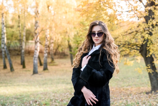 Beautiful young woman in a fur coat in the magical autumn forest.