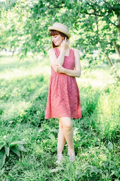 Beautiful young woman in the garden. A girl in a straw hat