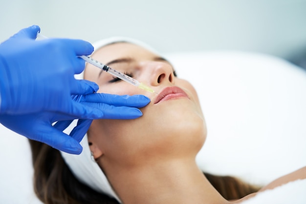 Beautiful young woman getting a acid face treatment at beauty salon.