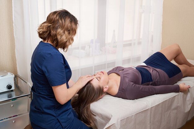 Beautiful Young Woman Getting a Face and head Treatment at Beauty Salon