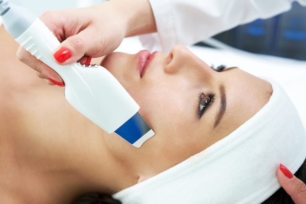 Beautiful young woman getting a face treatment at beauty salon.