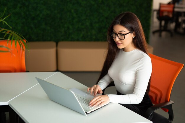 beautiful young woman in glasses at the table with laptop in the office