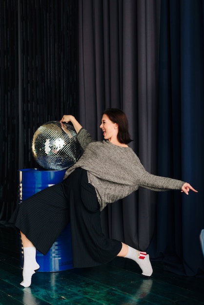 Beautiful young woman in grey sweater and disco ball at home