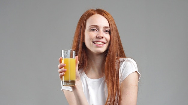 행복 하 고 오렌지 주스를 마시는 아름 다운 젊은 여자. 오렌지 주스 잔을 들고 젊은 여자