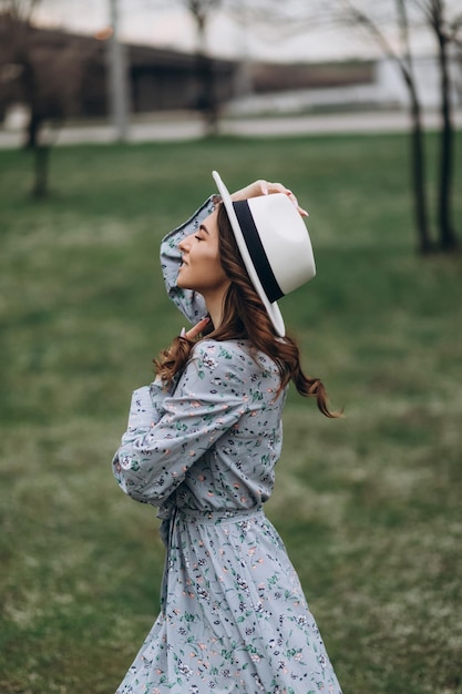 Beautiful young woman in a hat and dress on the background of a field with flowers spring