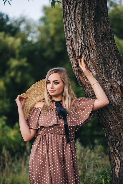 Beautiful young woman in a hat and dress walks in nature in autumn.