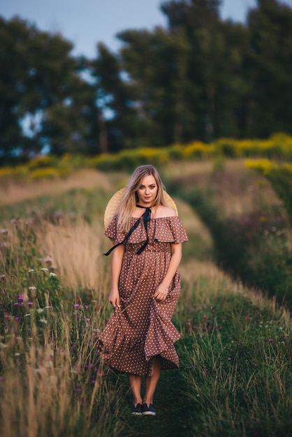 Beautiful young woman in a hat and dress walks in nature in autumn.