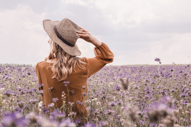 Beautiful young woman in Hat in lavender field. blooming flowers