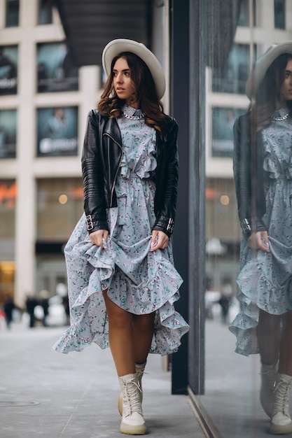 Beautiful young woman in a hat and leather jacket near the mall purchases shopping