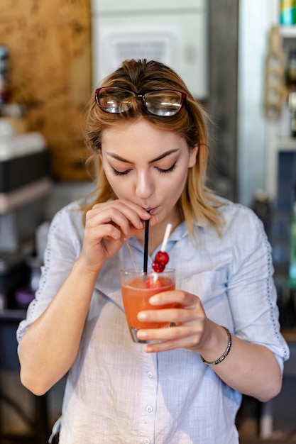 バーでドリンクを持っている美しい若い女性