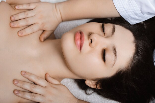 Beautiful young woman having facial massage while being in a wellness spa.