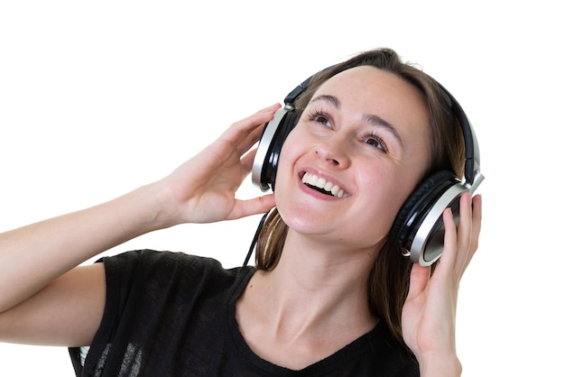 Beautiful young woman in headphones listening to music and dancing singing on white background