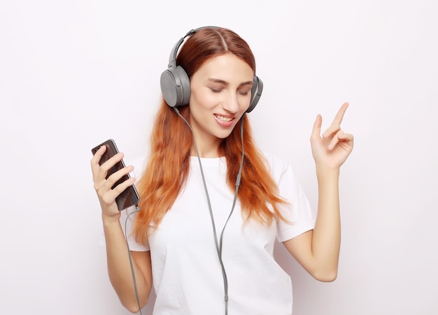 Beautiful young woman in headphones listening to music on white background