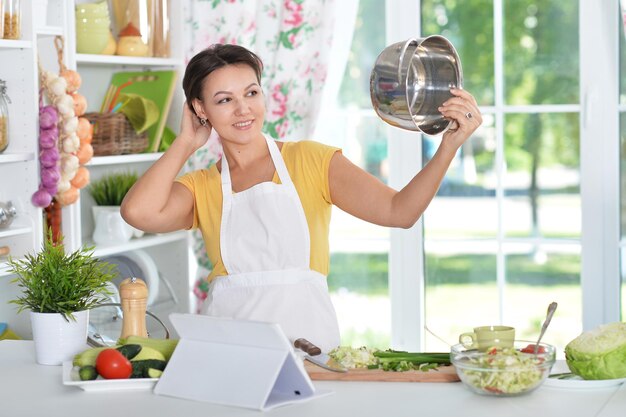 キッチンで夕食を準備するヘッドフォンで美しい若い女性