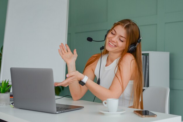 beautiful young woman in a headset communicates online with a laptop in the office lifestyle f