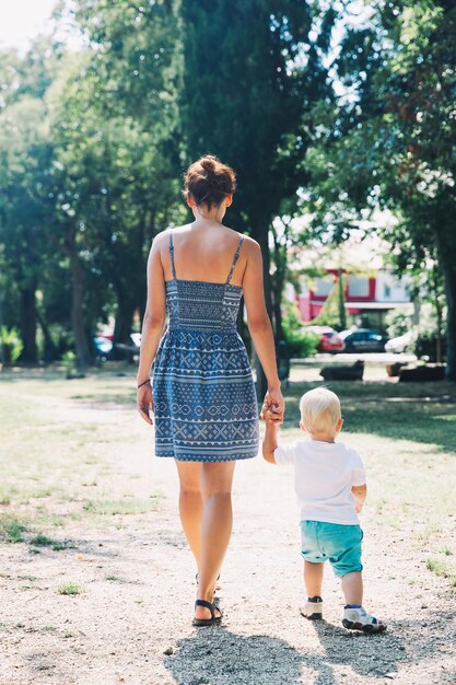 Beautiful young woman and her child spend time in the park at summer time