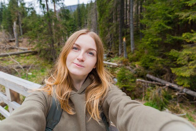 Beautiful young woman hiker taking selfie in the mountain forest