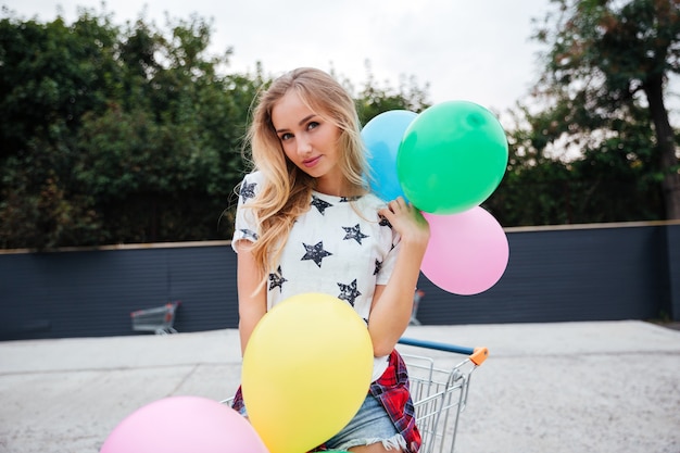 Beautiful young woman holding air balloons outdoors