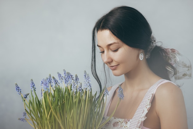 春の花の花束を保持している美しい若い女性官能的なロマンチックな混血の女性