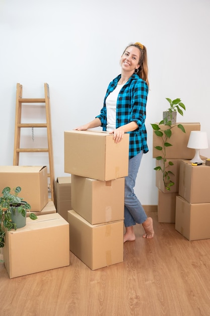 Beautiful young woman holding cardboard box at new apartment smiling very happy moving to new house